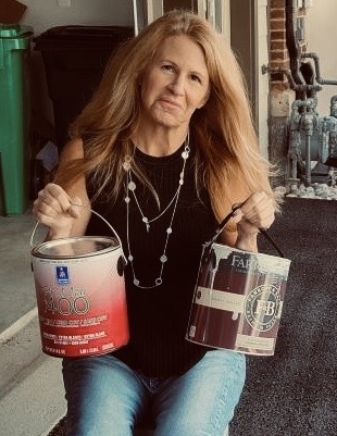 Deb Andrews looking sad while holding two paint cans.