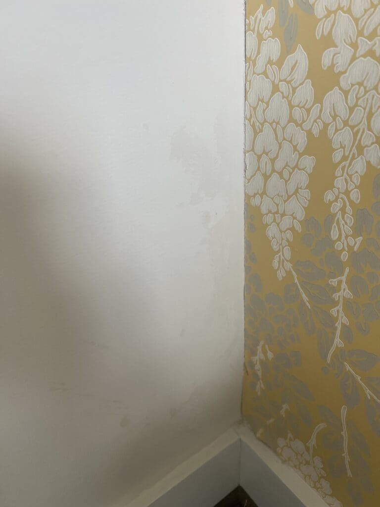 Close-up of a wall corner with a messy paint job, featuring uneven brushstrokes, drips, and overlapping colors.